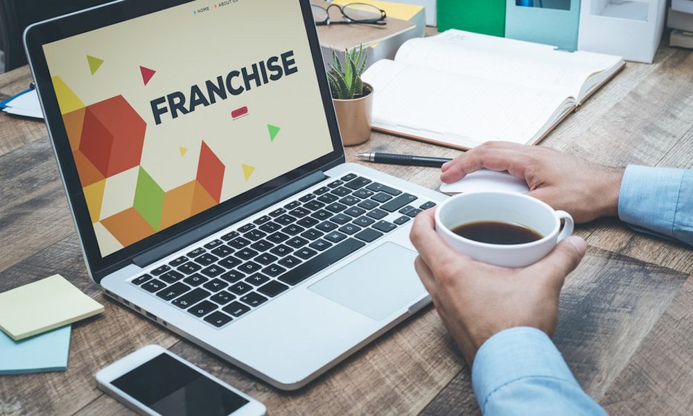 What Insurance Does Your Franchise Business Need - Person working with a cup of coffee on a laptop showing the words 'franchise'