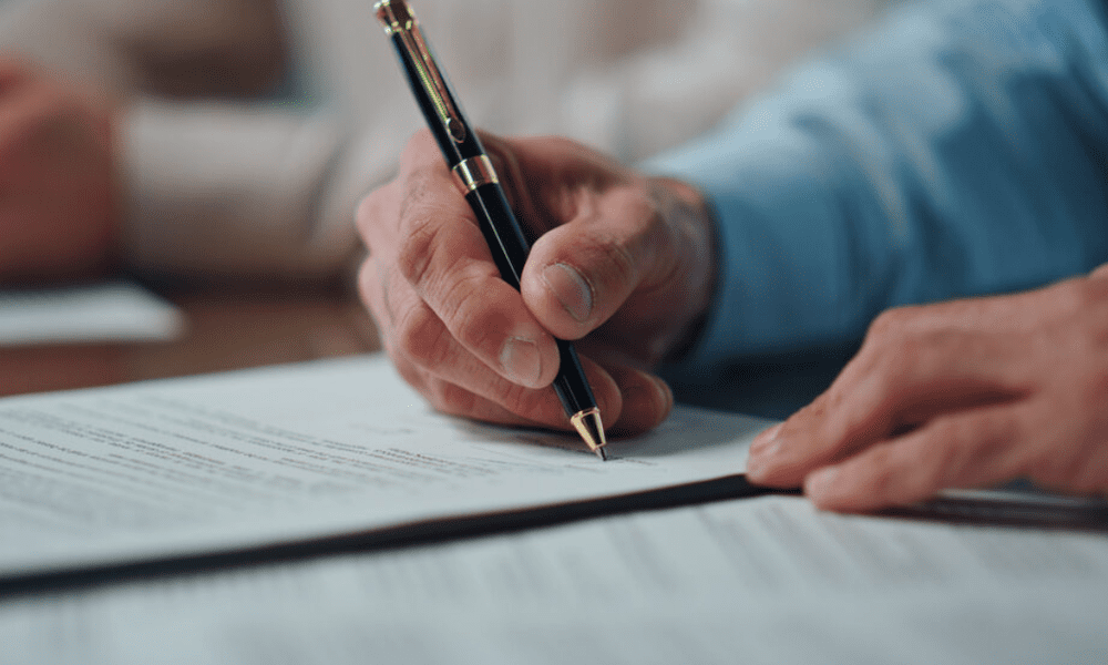 What Businesses Need To Know About the FTC’s New Noncompete Rule - Person's hands signing a document